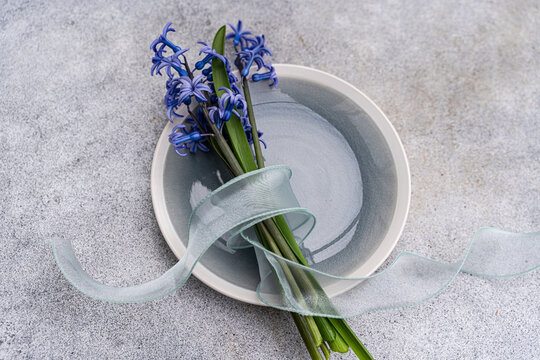 Overhead view of a bunch of fresh blue hyacinths tied with a ribbon on a ceramic plate on a table