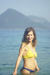 Obraz premium Woman in shallow Adriatic water with soft smile and direct gaze in natural light. Reveals independent female journey, quiet confidence in solo coastal exploration, and relaxed summer atmosphere.