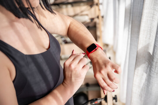 Woman checks fitness tracker during reformer studio workout