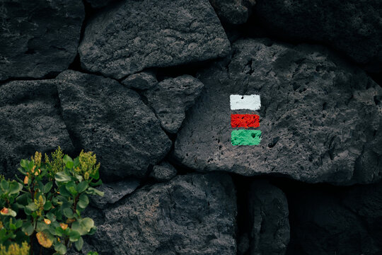 Hiking trail marker on volcanic rock wall in La Palma