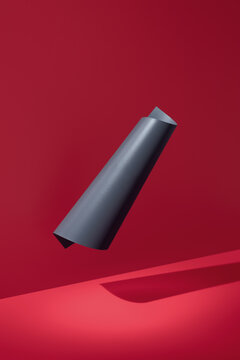 Curved abstract black paper shape on red minimal backdrop