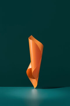 Curved abstract orange ribbon sculpture on dark teal background