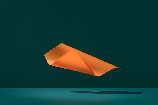 Minimal curved orange abstract paper shape on dark teal