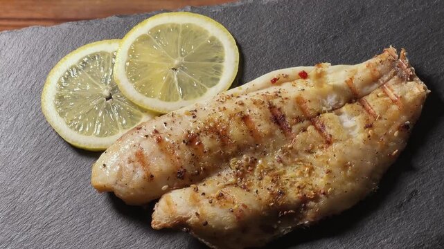 Serving of grilled gilthead fillet on skin on slate plate