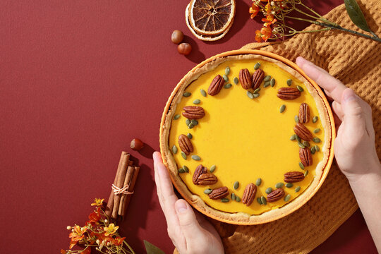 Hands holding pumpkin pie with pecans and autumn spices