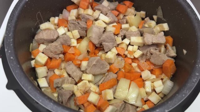 Meat with vegetables stewing in multi-cooker during goulash cooking