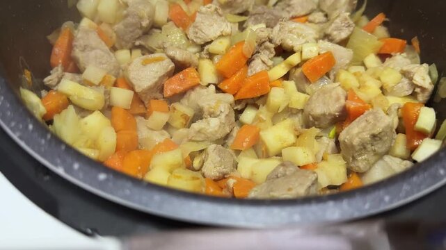 Meat with vegetables stewing in multi-cooker during goulash cooking