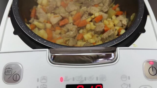 Meat with vegetables stewing in multi-cooker during goulash cooking