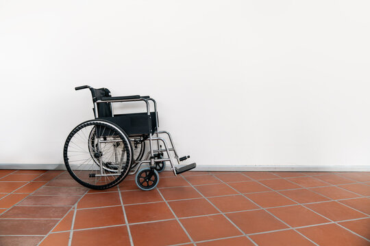 Empty Wheelchair Against White Wall in Minimal Interior Space