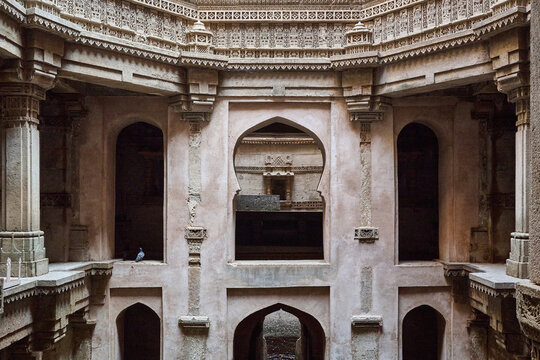 Arched openings and stone railings with a pigeon perched on a ledge inside Adalaj Stepwell, Adalaj ni Vav, Ahmedabad, Gujarat, India, Asia.