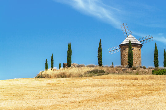 Traditional windmill above golden wheat field at harvest time