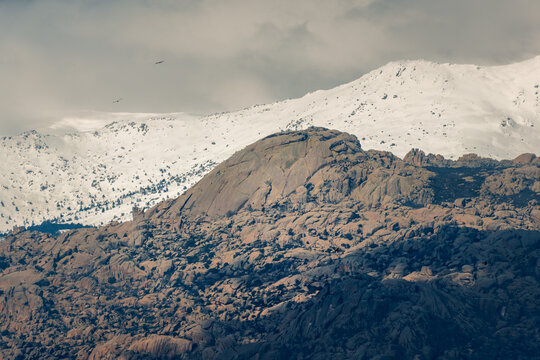Rocky mountain ridge with snowy peak under cloudy sky