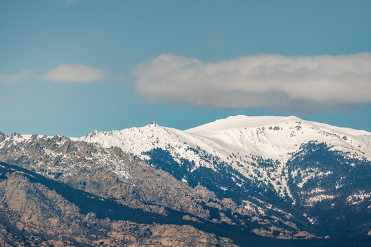 Snowy mountain ridge under blue sky with soft clouds
