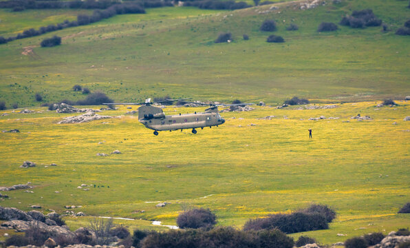 Military helicopter landing in spring meadow landscape