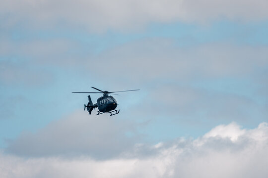Helicopter flying in cloudy blue sky with copy space