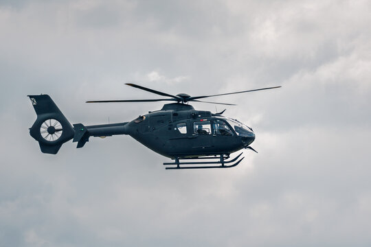 Modern helicopter flying in cloudy sky with copy space