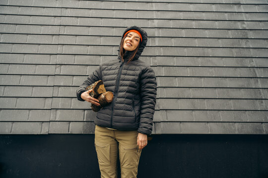 Person holding firewood outside a rural cabin on rainy day