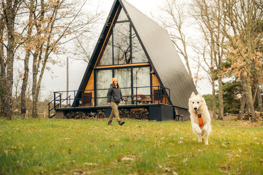 Rural A-frame cabin getaway with dog running on lawn