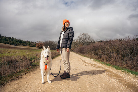 Rural woman walking white dog on country dirt road