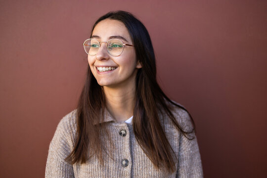 Smiling woman in business attire against brown background