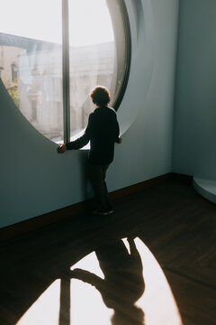 Child looking through large round window in modern museum