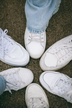 Group of friends in white sneakers standing in a circle