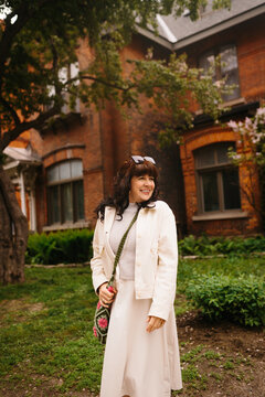 Smiling woman in light coat outside historic brick house