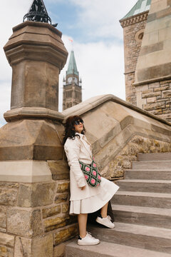 Tourist in coat leaning on stone steps near Parliament Hill
