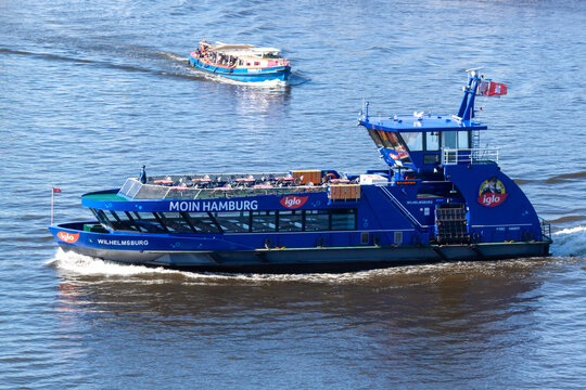 HADAG ferry "Wilhelmsburg" with "Moin Hamburg" and "Iglo" branding cruising on the Elbe River. Modern passenger water transport in the Port of Hamburg, Germany