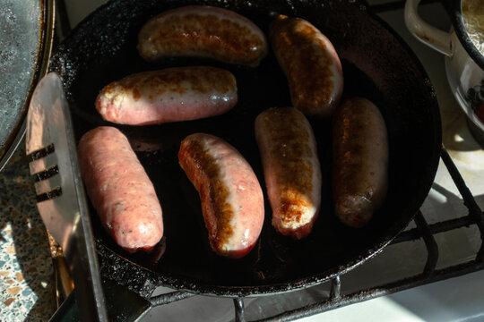 Fatty and tasty pork sausages are fried in a frying pan