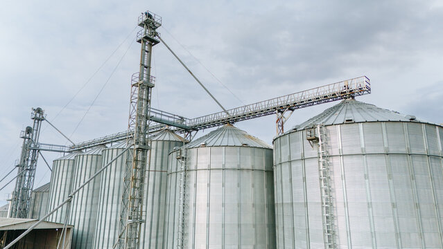 Aerial view of gleaming silver silos stretch skyward under a muted sky, their metallic surfaces reflecting the diffused light, Sremska Mitrovica, Vojvodina, Serbia.
