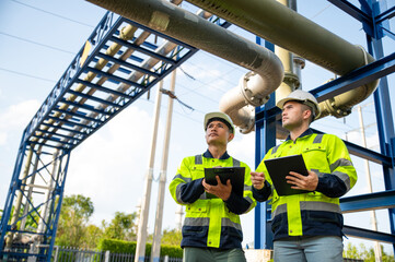 Fototapeta premium Engineers Inspecting Pipeline System with Clipboard at Industrial Energy Facility