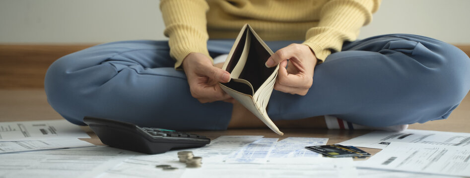 The stressed person sitting on the floor opening empty wallet