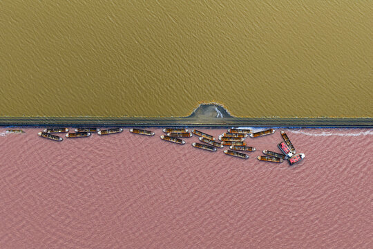 Aerial view of boats contrasting against the pink salt lake and adjacent yellow waters, creating a striking visual divide, San Pedro del Pinatar, Region of Murcia, Spain.