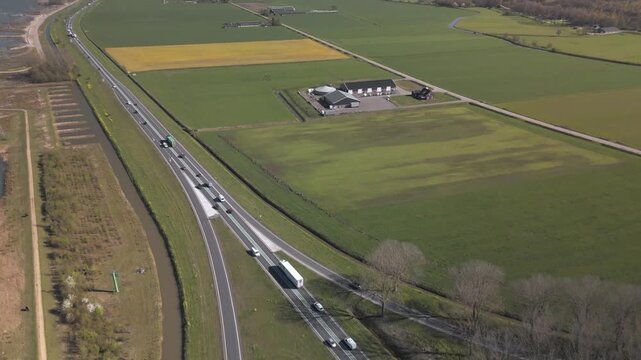 Aerial view of highway traffic through Dutch countryside near a lake