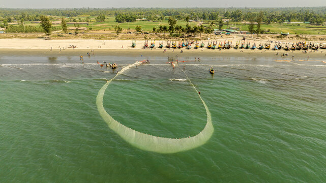 Aerial view of fishing nets cast a shimmering circle in the turquoise sea, against the backdrop of sandy shores, Cox's Bazar, Chittagong Division, Bangladesh.