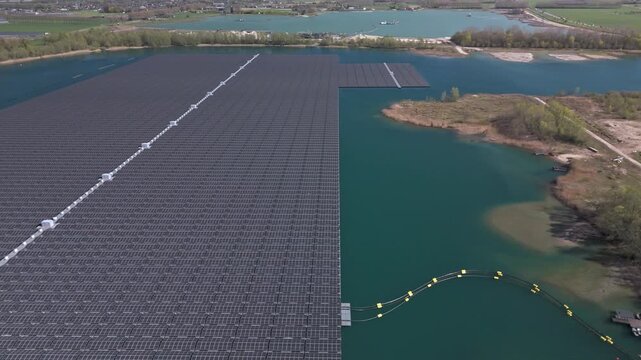 Aerial sideways reveal of large scale floating solar farm on a lake