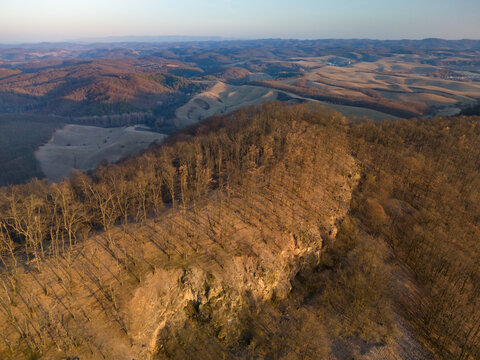 Aerial view of a rugged, rocky ridge cloaked in leafless trees under the diffused light of a winter's day, Cerova vrchovina, Banska Bystrica Region, Slovakia.