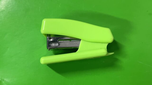 Bright Lime Green Plastic Stapler Lying on Solid Green Background Office Supply Studio Photography