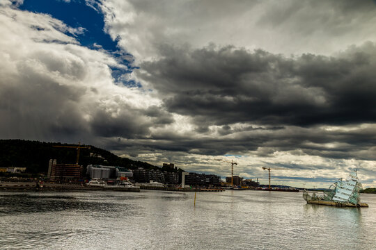 View of a cloudy skyline over the calm waters with construction cranes dotting the landscape, creating a contrast between nature and industry, West Old Town, New Mexico, Sweden.