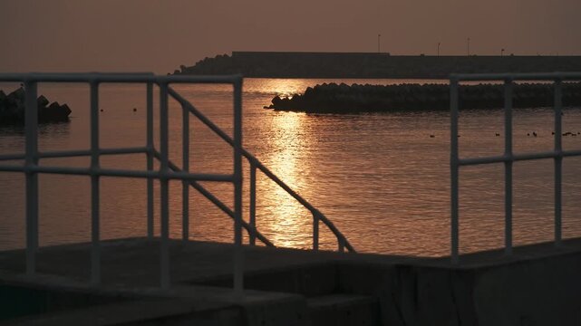 防波堤の階段から見る波けしブロックのある夕日の海