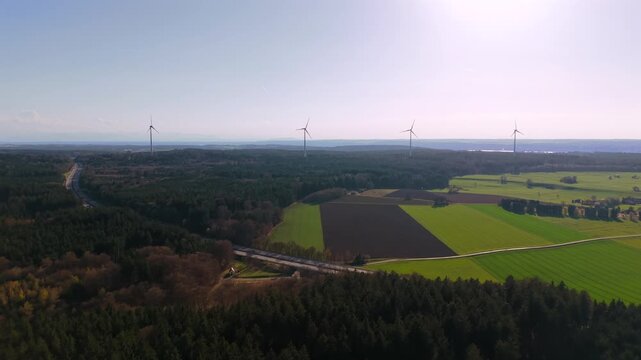Aerial drone view of wind turbines near Starnberg, Bavaria, Germany. Wind farm with modern windmills and power turbines across fields and forest, clean renewable energy concept.
