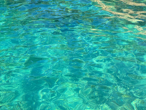 Clear emerald blue sea water with ripples on the calm surface.