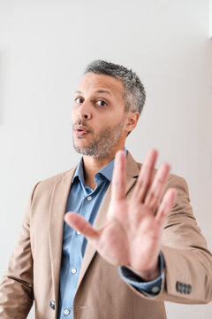 Mature businessman holding hand up in stop or wait gesture