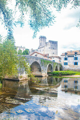 Obraz premium Ancient stone bridge and medieval water mill reflected in the river at Bourdeilles, Dordogne, France. Scenic summer landscape with historic architecture and lush greenery