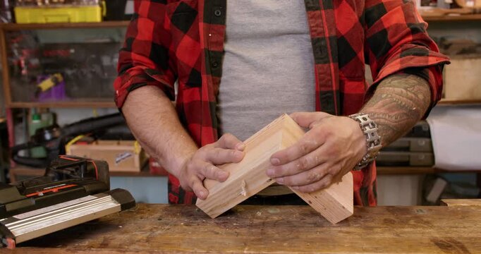 Wood assembling. Nail gun work. Male carpenter hand holding plank part together connecting two pieces of lumber in joinery workplace.