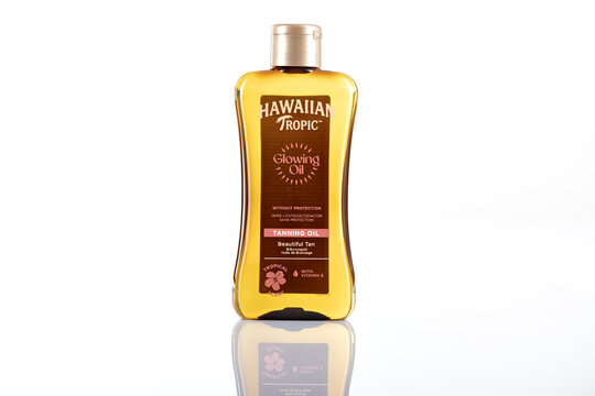Hawaiian Tropic Glowing Oil tanning oil bottle photographed isolated on white background. Cosmetic sun tanning product packaging shown as illustrative editorial.