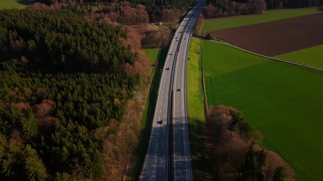 High angle view of the A95 motorway junction near Starnberg. A vital transport link and European route E533 through the alpine upland, surrounded by dense forest and nature.