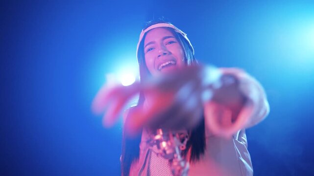 Young asian reggaeton singer performing her song. Talented girl rapping and dancing with passion in front of a microphone in a studio