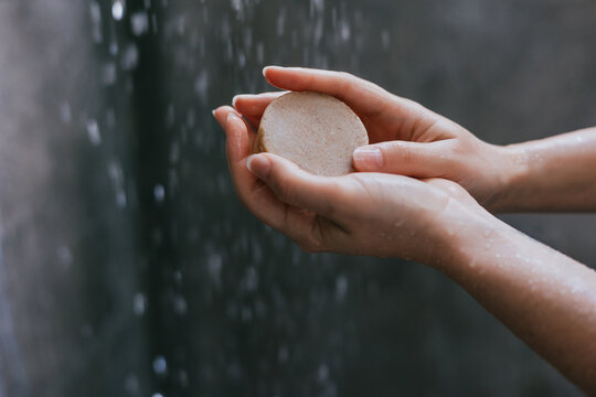 hands of young woman holding soap bar to take a shower at bathroom